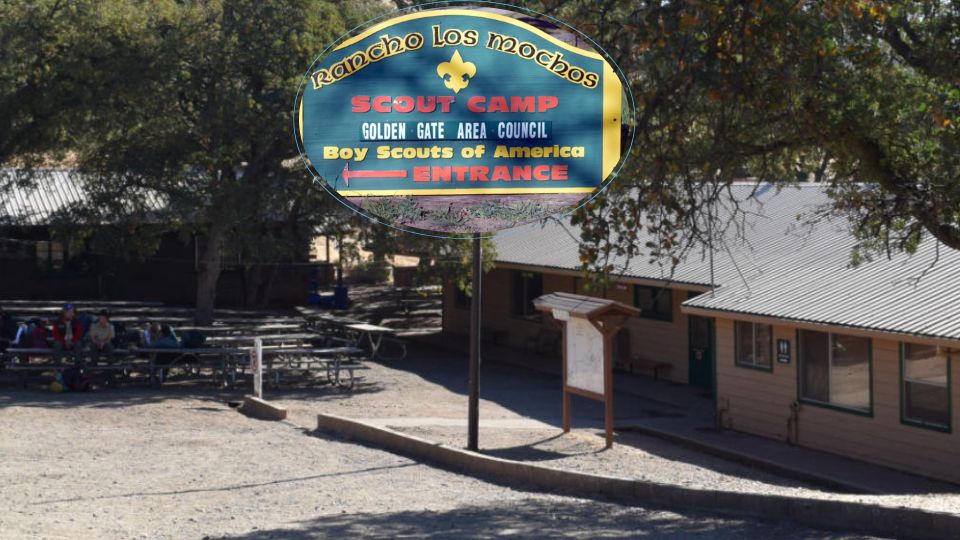 Rancho Los Mochos street sign with a background showing Teel Lodge and outdoor seating aea