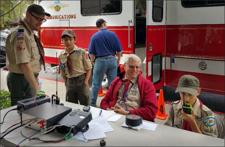 Scout talking on a walkie talkie with Fire Department communication truck n the background